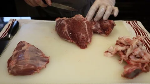 Man Cutting and trimming Large Pork Meat In A Kitchen With Two Knives Stock Footage 140558458