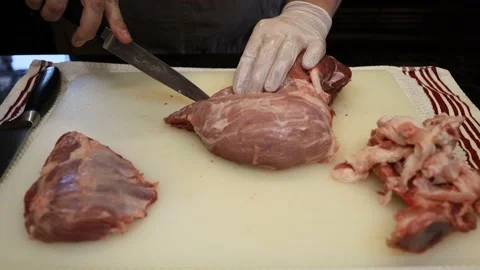 Man Cutting and trimming Large Pork Meat In A Kitchen With Two Knives Stock Footage 140558819