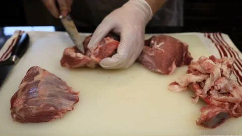 Man Cutting and trimming Large Pork Meat In A Kitchen With Two Knives Stock Footage 140559006