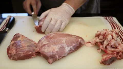 Man Cutting and trimming Large Pork Meat In A Kitchen With Two Knives Video stock 140559261
