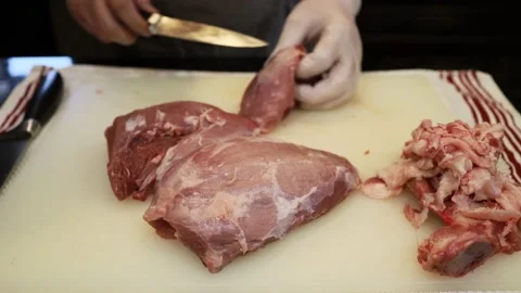 Man Cutting and trimming Large Pork Meat In A Kitchen With Two Knives Stock Footage 140560026