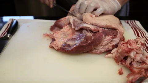 Man Cutting and trimming Large Pork Meat In A Kitchen With Two Knives Stock Footage 140560800