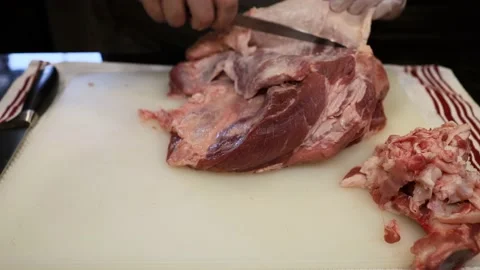 Man Cutting and trimming Large Pork Meat In A Kitchen With Two Knives Stock Footage 140560852
