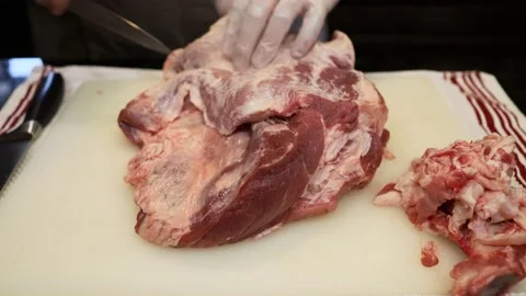 Man Cutting and trimming Large Pork Meat In A Kitchen With Two Knives Stock Footage 140560969