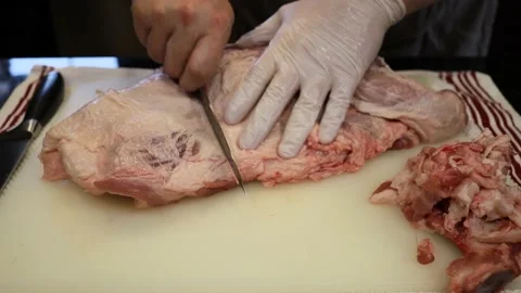 Man Cutting and trimming Large Pork Meat In A Kitchen With Two Knives Stock Footage 140561002