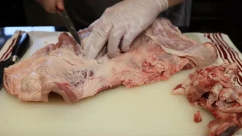 Man Cutting and trimming Large Pork Meat In A Kitchen With Two Knives Video stock 140561372