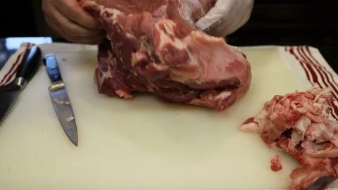 Man Cutting and trimming Large Pork Meat In A Kitchen With Two Knives Stock Footage 140561650