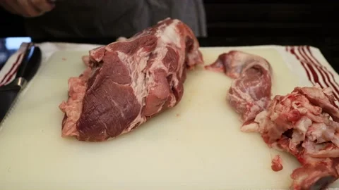 Man Cutting and trimming Large Pork Meat In A Kitchen With Two Knives Stock Footage 140561732