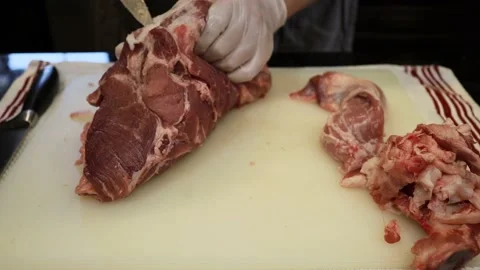 Man Cutting and trimming Large Pork Meat In A Kitchen With Two Knives Stock Footage 140561898