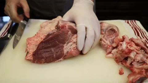 Man Cutting and trimming Large Pork Meat In A Kitchen With Two Knives Video stock 140561944
