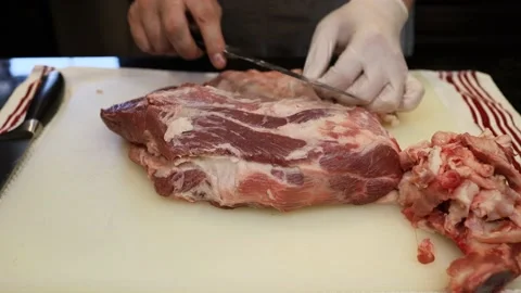 Man Cutting and trimming Large Pork Meat In A Kitchen With Two Knives Video stock 140562876
