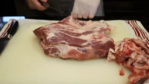 Man Cutting and trimming Large Pork Meat In A Kitchen With Two Knives Stock Footage 140563185