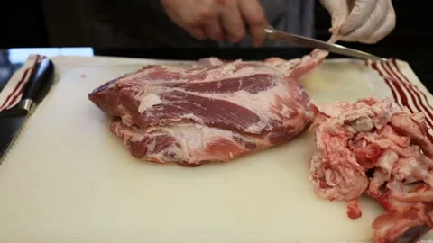 Man Cutting and trimming Large Pork Meat In A Kitchen With Two Knives Stock Footage 140564217