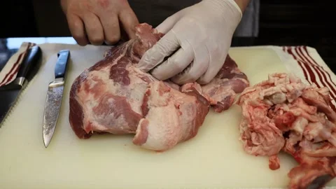 Man Cutting and trimming Large Pork Meat In A Kitchen With Two Knives Stock Footage 140564654