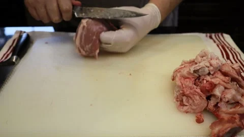 Man Cutting and trimming Large Pork Meat In A Kitchen With Two Knives Stock Footage 140564796