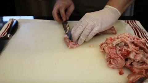 Man Cutting and trimming Large Pork Meat In A Kitchen With Two Knives Stock Footage 140568923