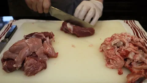 Man Cutting and trimming Large Pork Meat In A Kitchen With Two Knives Stock Footage 140569875