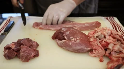 Man Cutting and trimming Large Pork Meat In A Kitchen With Two Knives Stock Footage 140570408