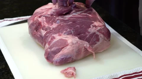 Man Cutting and trimming Large Pork Meat In A Kitchen With Two Knives Stock Footage 140598211