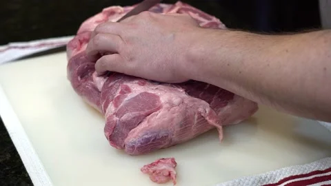 Man Cutting and trimming Large Pork Meat In A Kitchen With Two Knives Video stock 140598233
