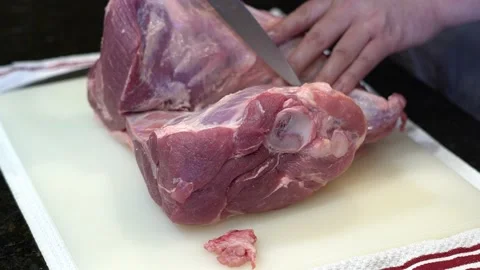 Man Cutting and trimming Large Pork Meat In A Kitchen With Two Knives Stock Footage 140598645