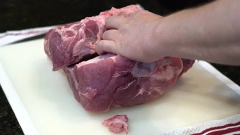 Man Cutting and trimming Large Pork Meat In A Kitchen With Two Knives Stock Footage 140598657