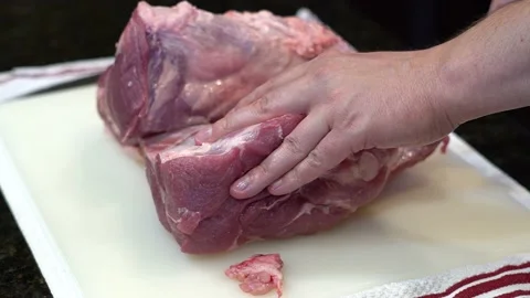 Man Cutting and trimming Large Pork Meat In A Kitchen With Two Knives Stock Footage 140599115