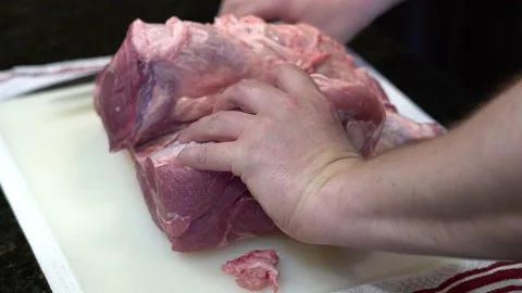 Man Cutting and trimming Large Pork Meat In A Kitchen With Two Knives Stock Footage 140599138