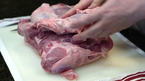 Man Cutting and trimming Large Pork Meat In A Kitchen With Two Knives Stock Footage 140599158