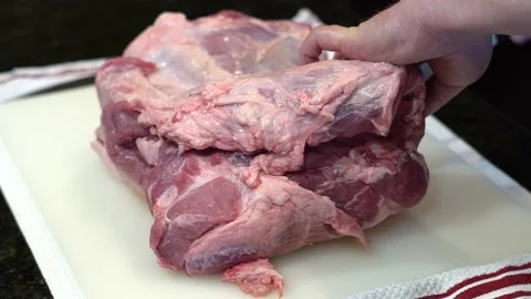 Man Cutting and trimming Large Pork Meat In A Kitchen With Two Knives Video stock 140599180