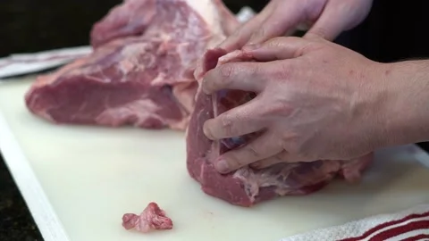Man Cutting and trimming Large Pork Meat In A Kitchen With Two Knives Stock Footage 140600067