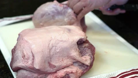Man Cutting and trimming Large Pork Meat In A Kitchen With Two Knives Video stock 140600519