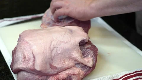 Man Cutting and trimming Large Pork Meat In A Kitchen With Two Knives Stock Footage 140600545