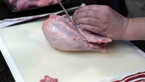 Man Cutting and trimming Large Pork Meat In A Kitchen With Two Knives Stock Footage 140600725