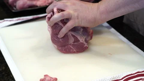Man Cutting and trimming Large Pork Meat In A Kitchen With Two Knives Video stock 140600930