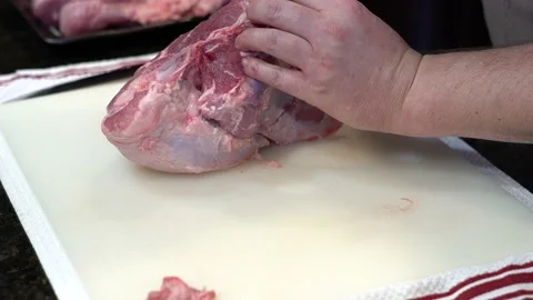 Man Cutting and trimming Large Pork Meat In A Kitchen With Two Knives Stock Footage 140601038