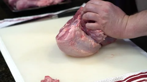 Man Cutting and trimming Large Pork Meat In A Kitchen With Two Knives Stock Footage 140601437