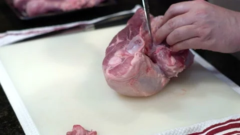 Man Cutting and trimming Large Pork Meat In A Kitchen With Two Knives Video stock 140601482