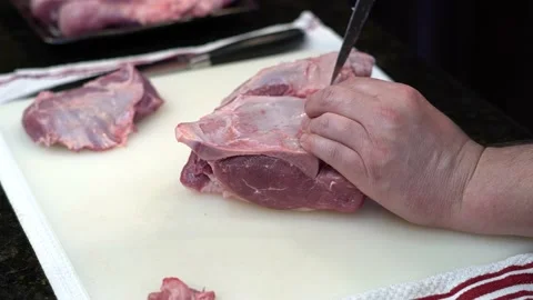 Man Cutting and trimming Large Pork Meat In A Kitchen With Two Knives Stock Footage 140601609