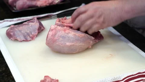 Man Cutting and trimming Large Pork Meat In A Kitchen With Two Knives Stock Footage 140601824