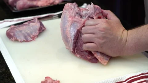 Man Cutting and trimming Large Pork Meat In A Kitchen With Two Knives Stock Footage 140601943
