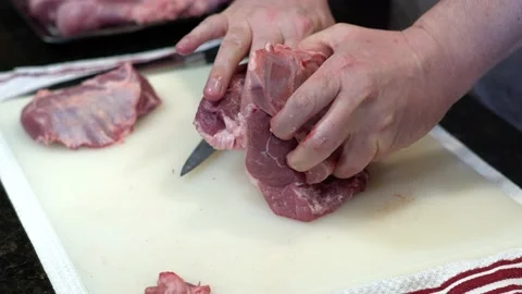 Man Cutting and trimming Large Pork Meat In A Kitchen With Two Knives Video stock 140602207
