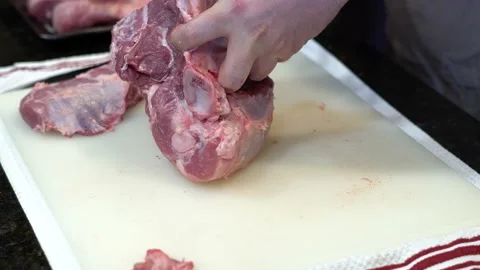 Man Cutting and trimming Large Pork Meat In A Kitchen With Two Knives Stock Footage 140602223