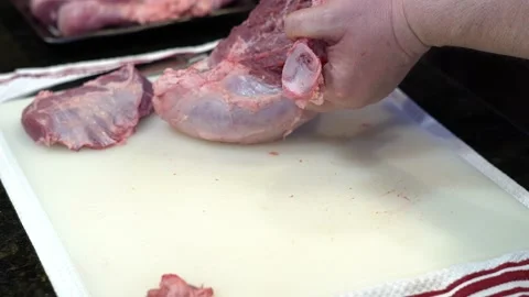 Man Cutting and trimming Large Pork Meat In A Kitchen With Two Knives Video stock 140602486