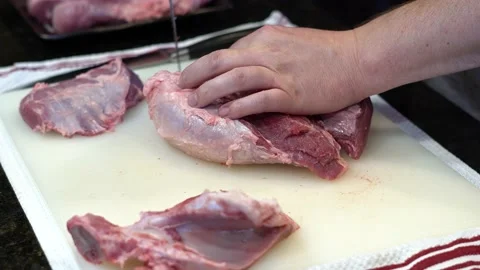 Man Cutting and trimming Large Pork Meat In A Kitchen With Two Knives Video stock 140602579