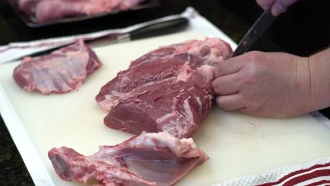 Man Cutting and trimming Large Pork Meat In A Kitchen With Two Knives Stock Footage 140602595