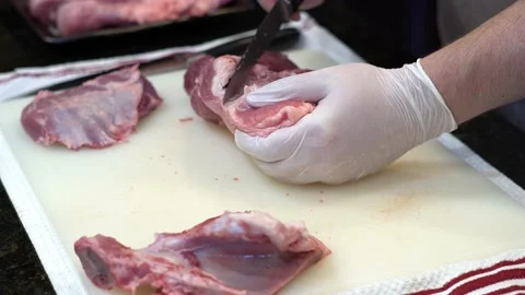 Man Cutting and trimming Large Pork Meat In A Kitchen With Two Knives Stock Footage 140603047