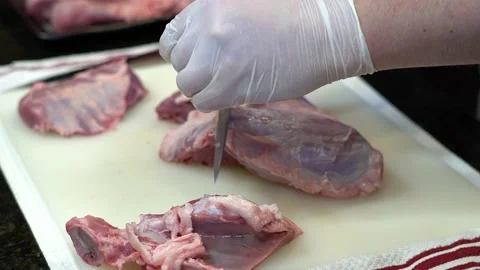 Man Cutting and trimming Large Pork Meat In A Kitchen With Two Knives Stock Footage 140603152