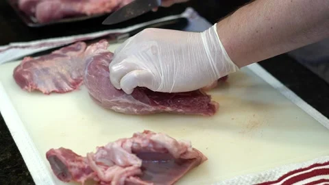 Man Cutting and trimming Large Pork Meat In A Kitchen With Two Knives Stock Footage 140603363