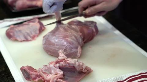Man Cutting and trimming Large Pork Meat In A Kitchen With Two Knives Video stock 140604361